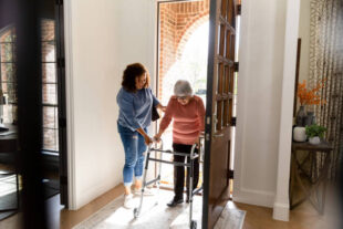 Individual helping an elderly person walk